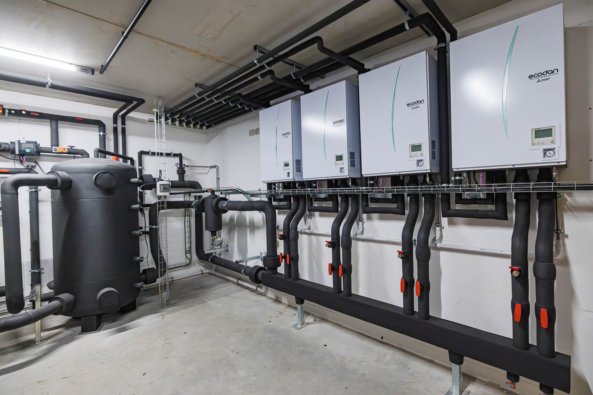 Wärmepumpen-Innengeräte mit Pufferspeicher und Verrohrung in einem Technikraum