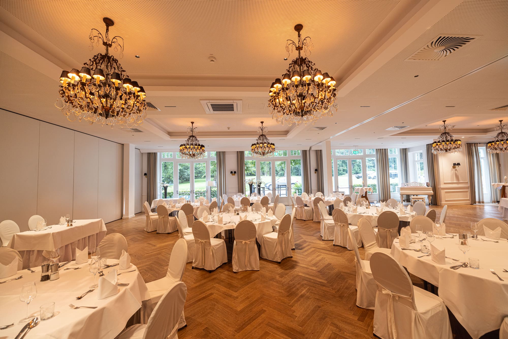 Festsaal mit Kronleuchtern, eingedeckten Tischen und Kassettengeräten in der Decke